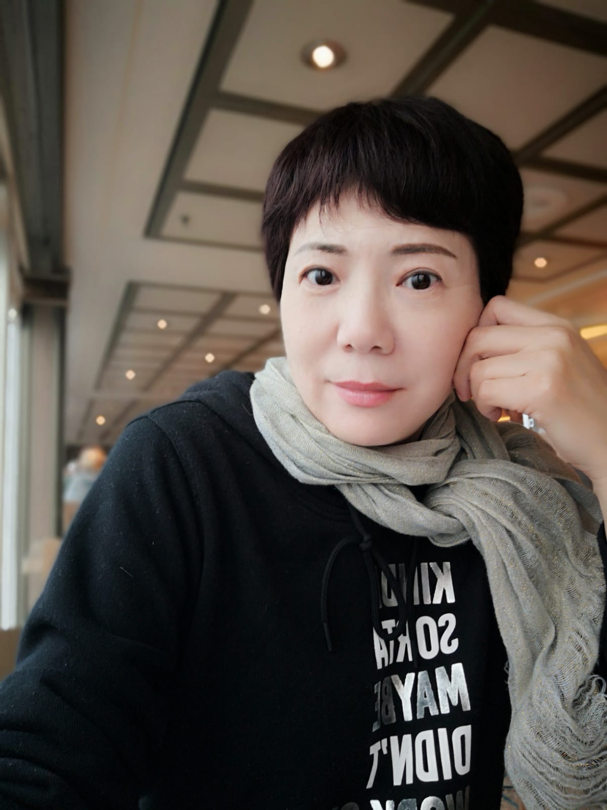 Nicole is posing for a picture and looking at the camera. She is smiling and resting her hand against the side of her face.